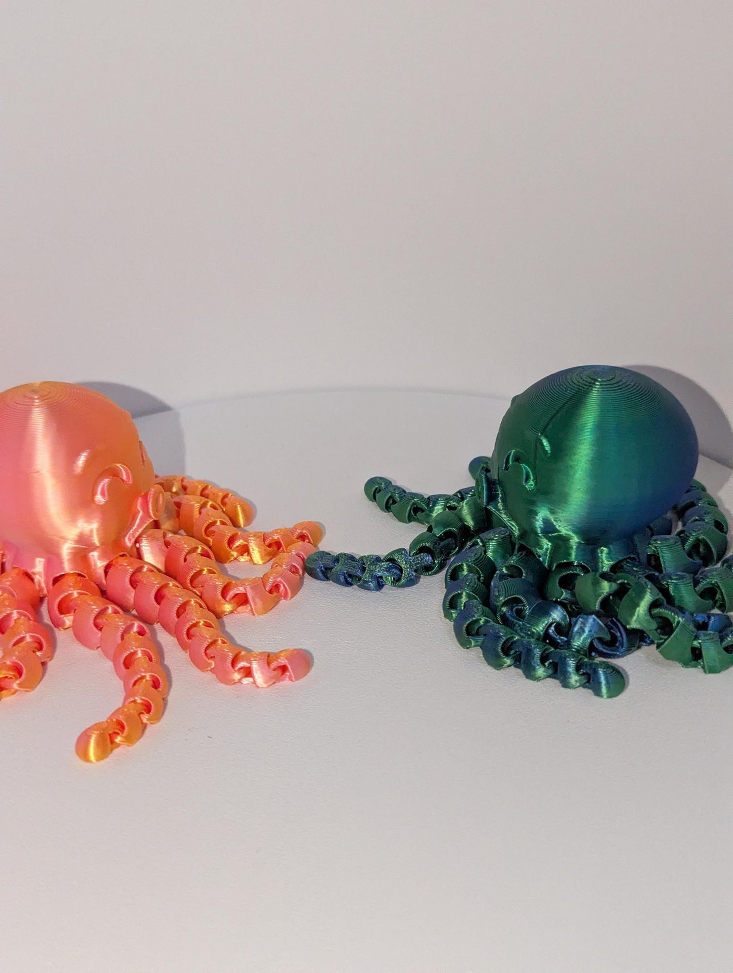 Featuring two articulated octopus looking at each other. One in Green one in orange.