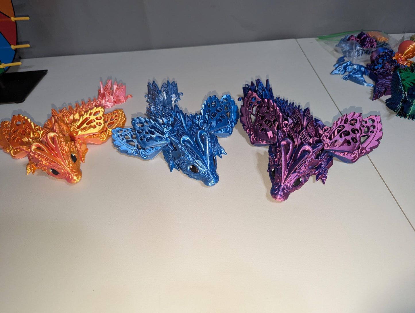 Winged baby dragons featuring three in orange/pink, blue/silver, and purple/blue.
