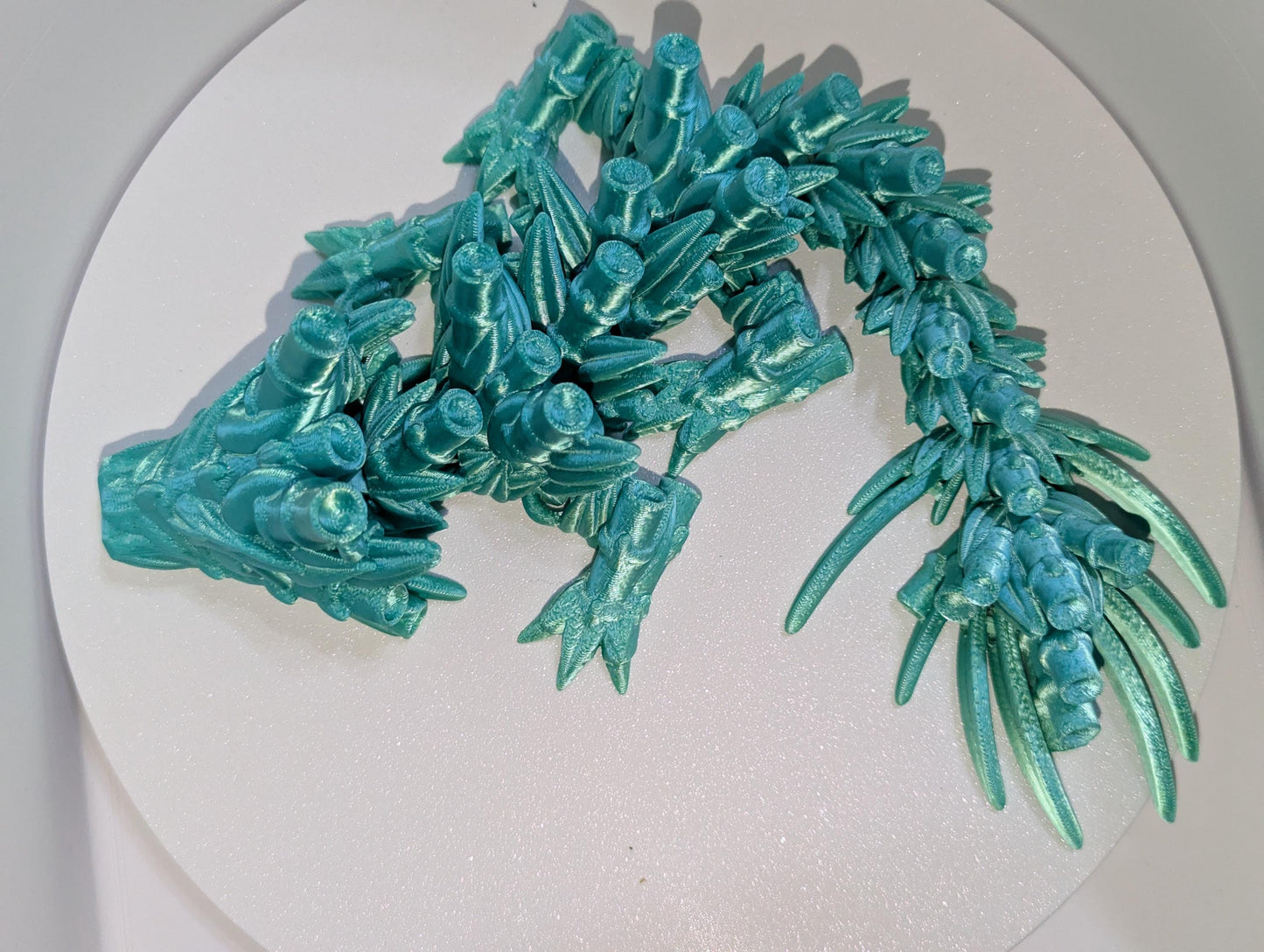 Curled up Green Translucent baby Bamboo Articulated dragon. Side Profile