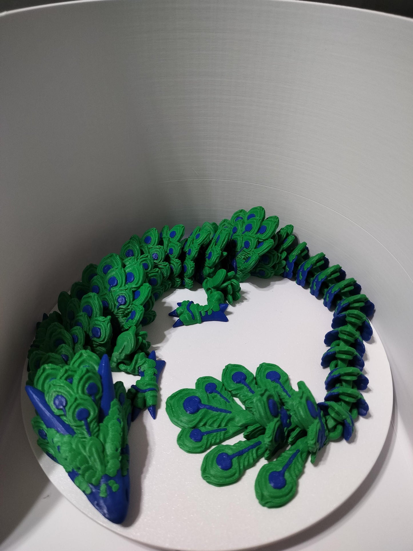 Peacock Articulated dragon featuring a rich green and blue color scheme.with out stretched feathered tail.